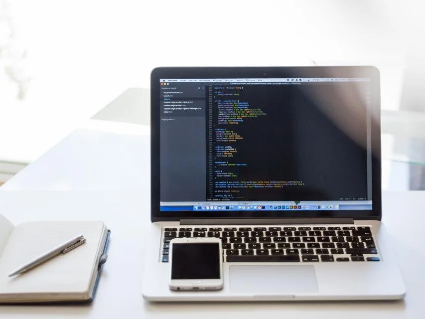 Laptop showing website code on a clean white desk